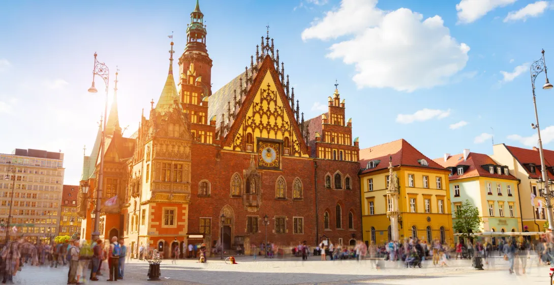 Historic Old Town Hall in Wrocław's Main Market Square, with blurred tourists and colorful surrounding buildings under a blue
