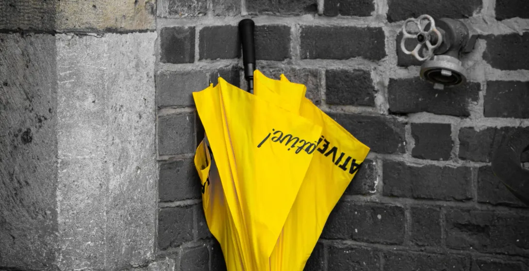 Yellow ACTIVE tours umbrella against a brick wall.