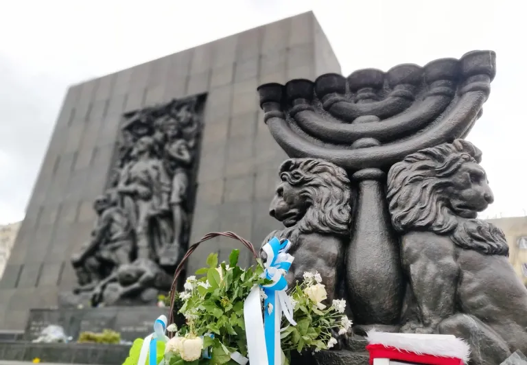 Warsaw Ghetto Memorial with menorah and flowers.