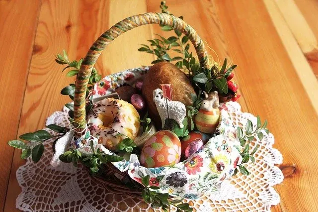 Tradycyjny polski koszyczek wielkanocny (Święconka) z chlebem, pączkiem, pisankami, czekoladą, barankiem i bukszpanem na serw