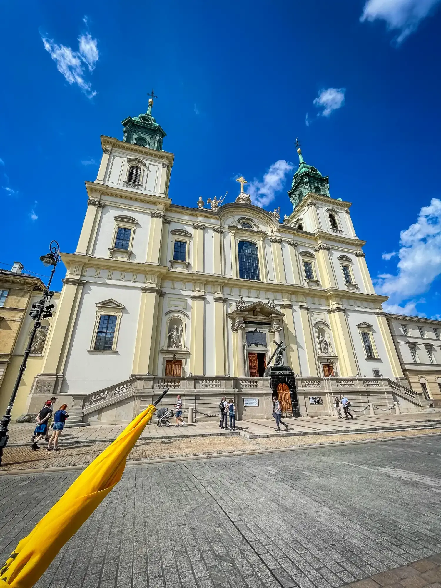 The neoclassical facade of the Carmelite Church in Warsaw against a bright blue sky.