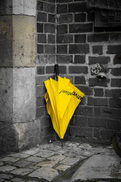 Yellow ACTIVE tours umbrella against a brick wall.