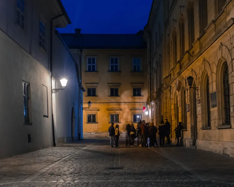 A guided tour group explores the charming, historic streets of Krakow at night.