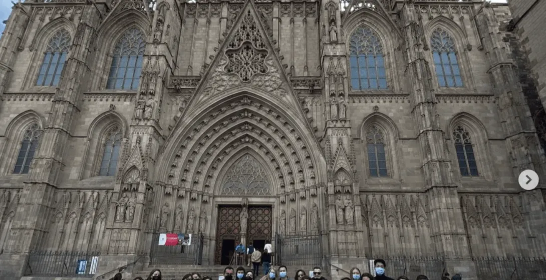 A large tour group smiles in front of the Barcelona Cathedral.