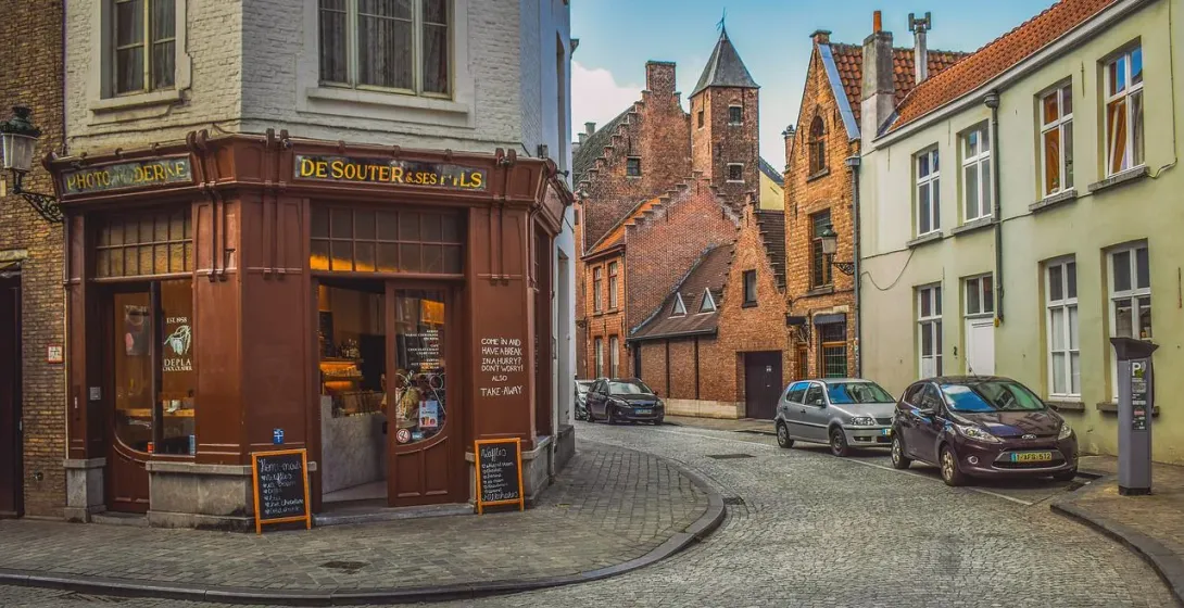 Charming cobblestone street in Bruges, Belgium, with historic buildings and a chocolate shop.