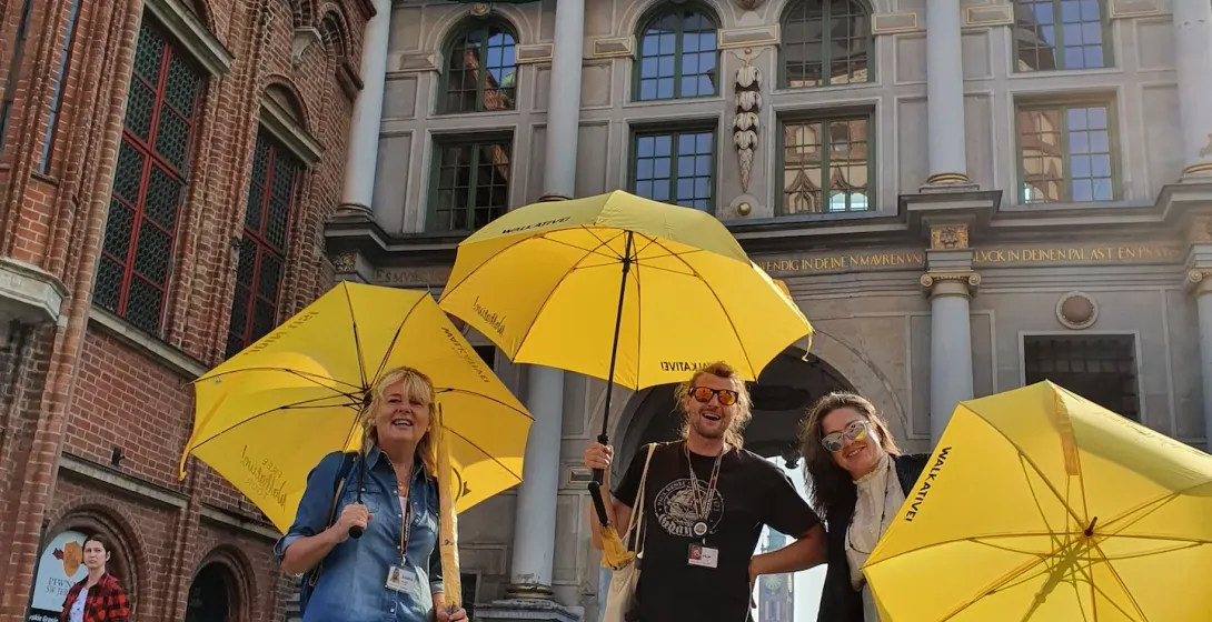 Happy tourists on a guided tour in Gdansk, Poland, standing in front of the Golden Gate.
