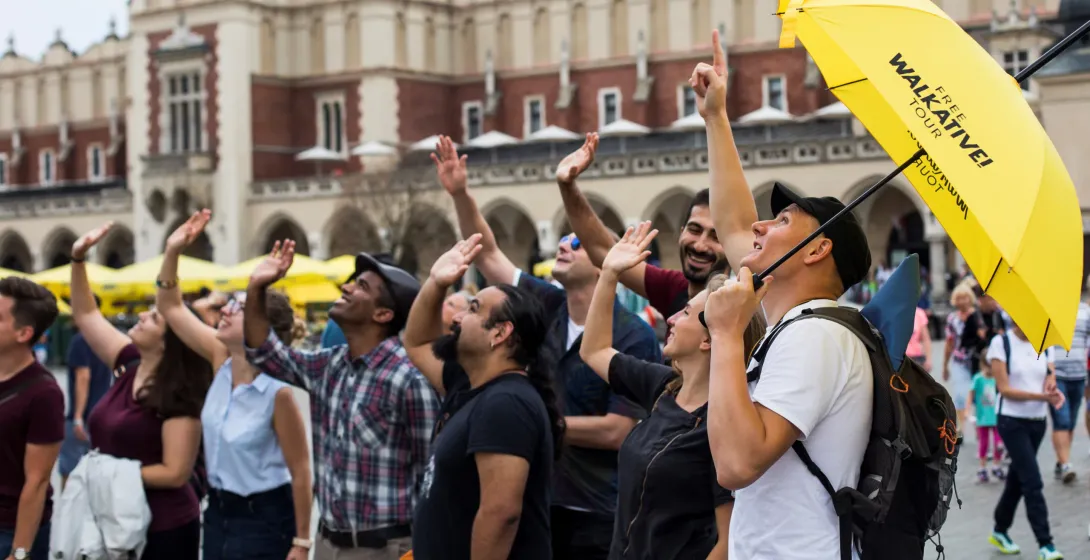 A Walkative! Free Tour guide leads a group of tourists in Krakow's Main Market Square.