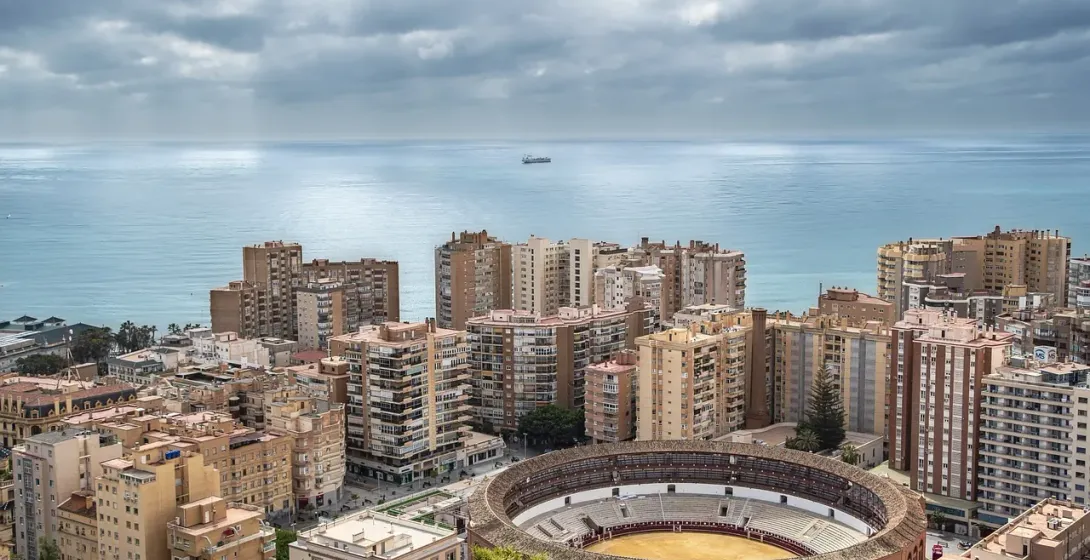 Aerial view of Malaga's bullring and cityscape overlooking the Mediterranean Sea.