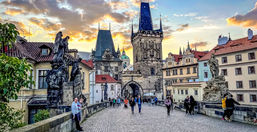 Tourists enjoying a sunset stroll across Prague's Charles Bridge.