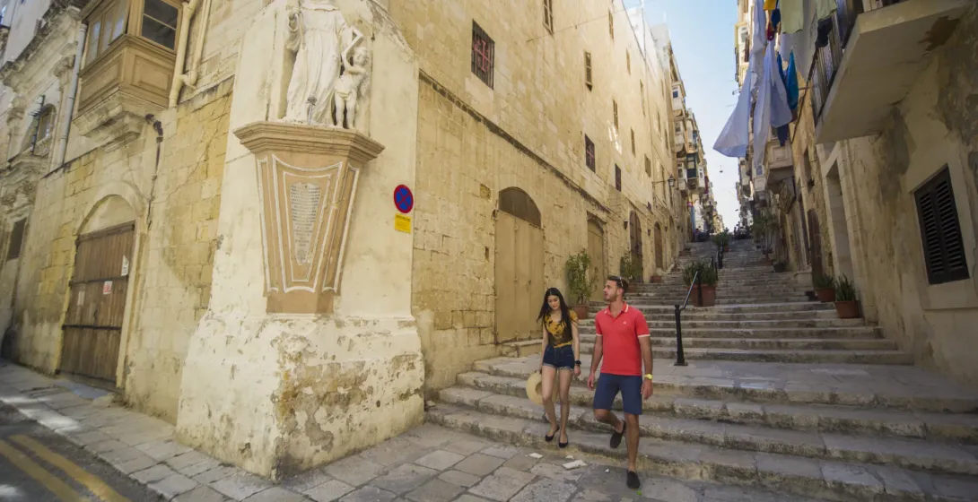 Couple walking up a historic staircase in Valletta, Malta.