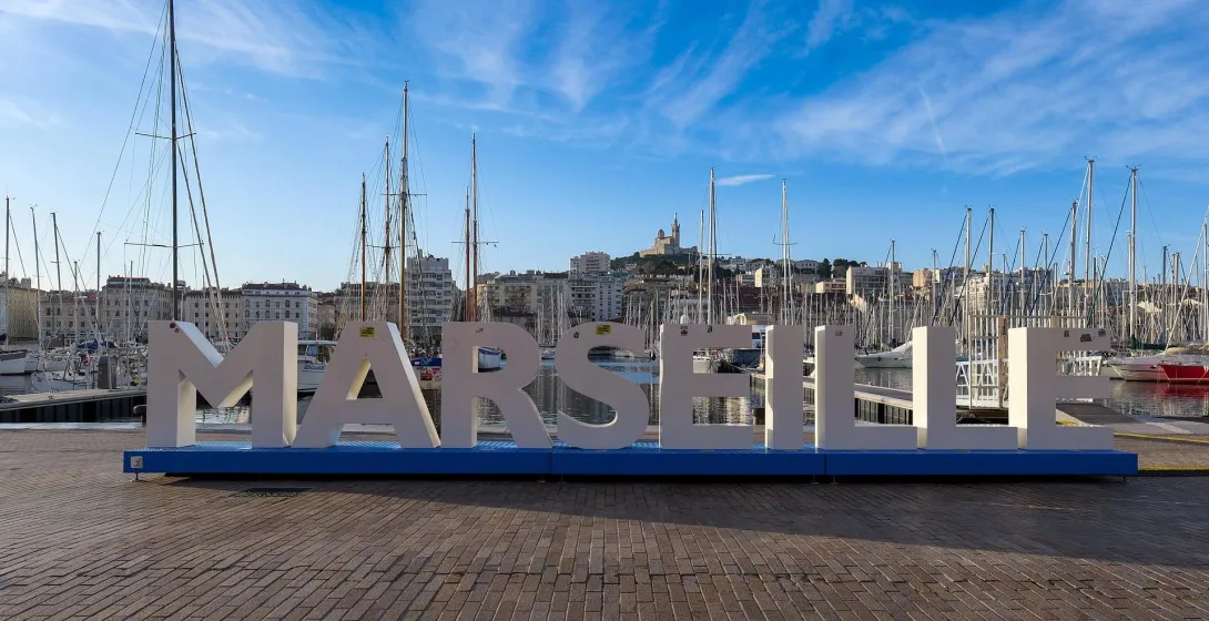 Marseille harbor with sailboats and city sign.