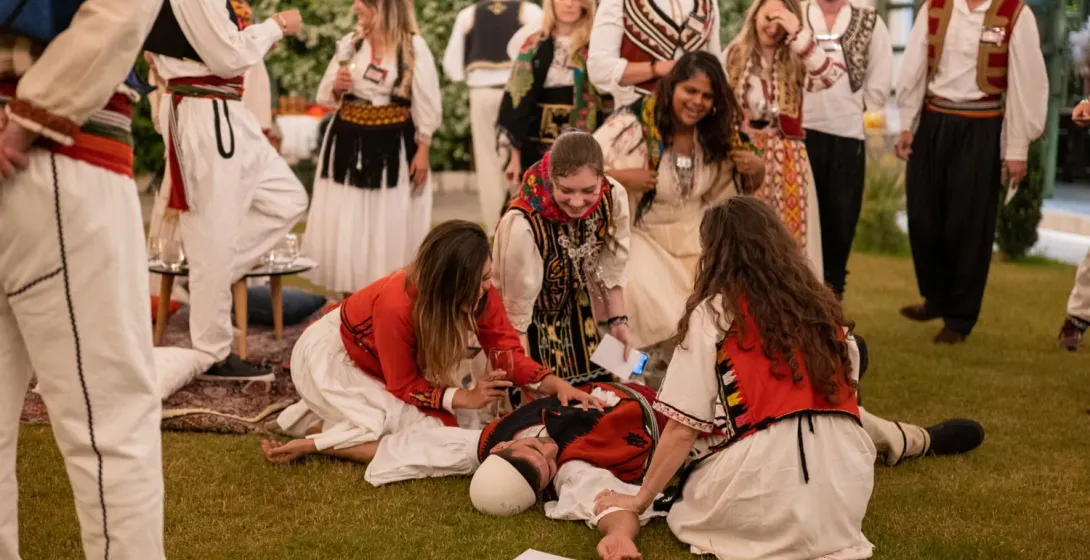 A group in traditional Balkan attire participates in a lively cultural performance.