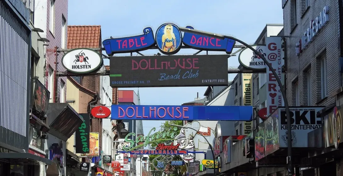 A vibrant street scene in a German city, filled with neon signs and advertisements.
