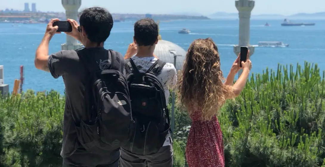 Tourists taking photos of a beautiful mosque and the Bosphorus in Istanbul.