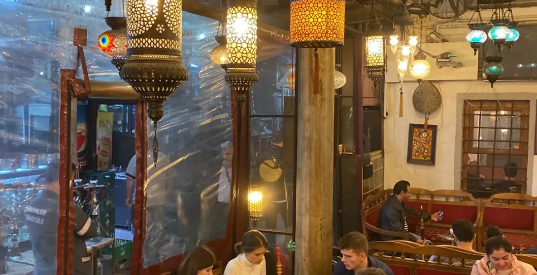 Cozy Istanbul tea house with ornate lamps and patrons enjoying tea.