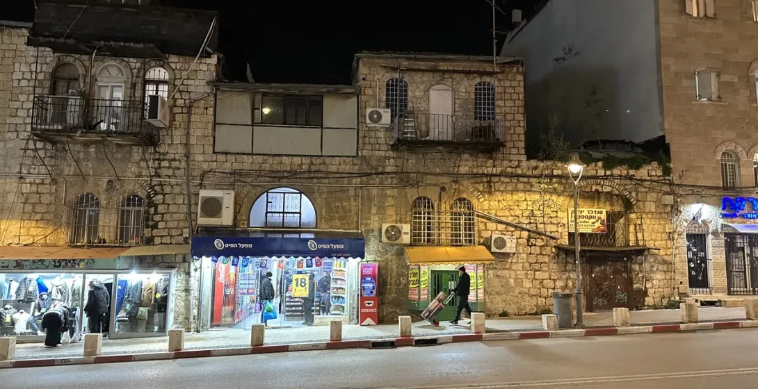 Night scene in Jerusalem's Old City, showing historic stone buildings and a quiet street.