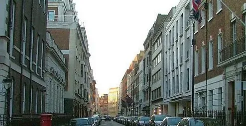 A tranquil street in London, England, lined with elegant buildings and parked cars.