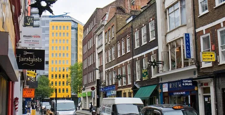 A bustling London street scene with shops and a black cab.