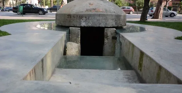 A preserved WWII bunker in a Rome park, partially submerged in water.