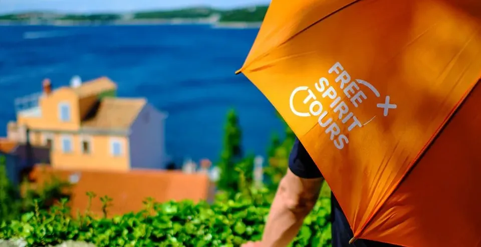 A Free Spirit Tours guide with an orange umbrella, enjoying a scenic view of Split, Croatia.