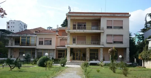 A pathway leads to a large building in a peaceful garden setting.