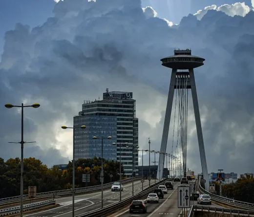 Dramatic view of Bratislava's UFO Bridge and observation tower under a stormy sky.