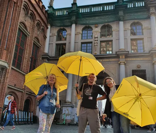 Happy tourists on a guided tour in Gdansk, Poland, standing in front of the Golden Gate.