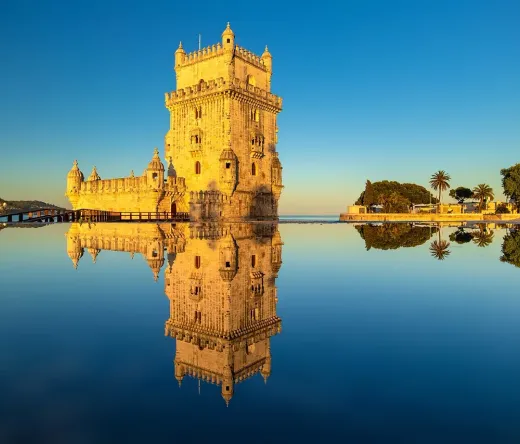 Belém Tower in Lisbon, Portugal, reflected in the water at sunrise.