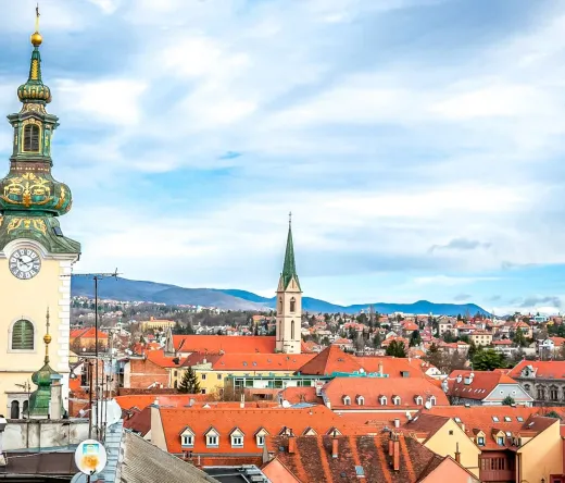 Panoramic view of Maribor, Slovenia, featuring a prominent clock tower and terracotta rooftops.