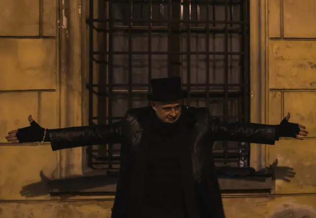 Tour guide in top hat in front of old building.