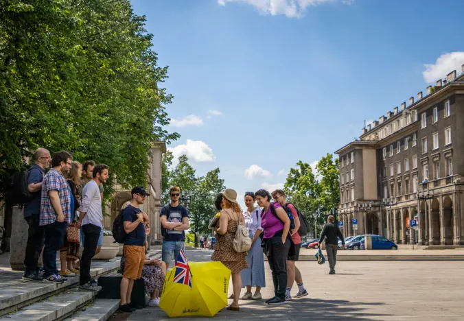 A guided tour group explores a sunny city square in Krakow, Poland.
