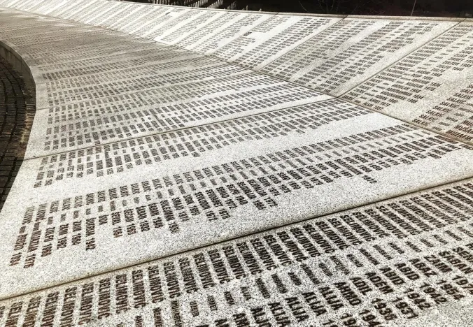 A curved memorial wall inscribed with numerous names and dates.