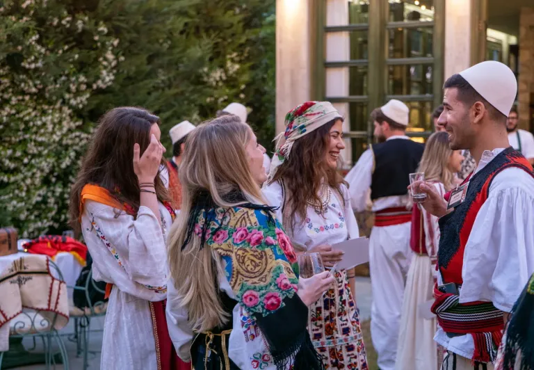 Tourists enjoying an Albanian Night show, interacting with performers in traditional clothing.