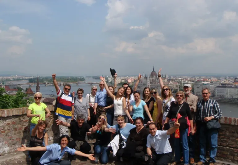 Happy tour group in Budapest, Hungary, with the Parliament Building in the background.