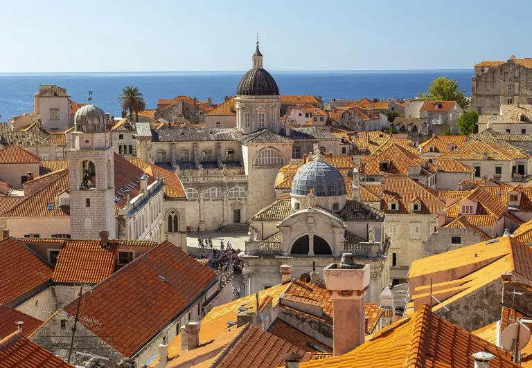 Aerial view of Dubrovnik's Old Town with terracotta roofs and the Adriatic Sea.
