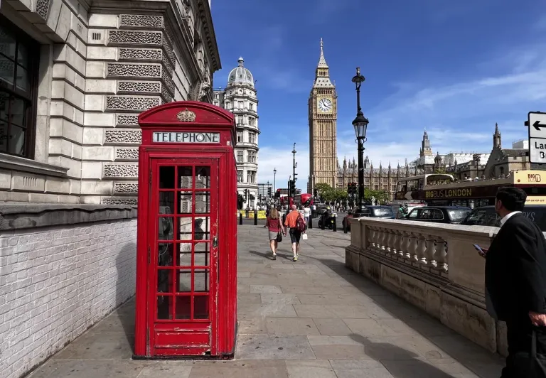 Iconic London scene: red phone booth, Big Ben, and Houses of Parliament.