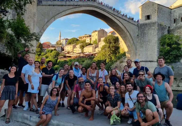 Happy tour group in Mostar, Bosnia and Herzegovina, posing with the Stari Most bridge.