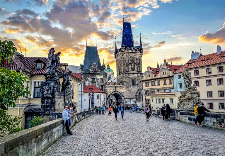 Tourists enjoying a sunset stroll across Prague's Charles Bridge.