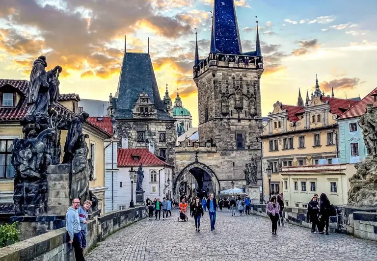 Tourists enjoying a sunset stroll across Prague's Charles Bridge.