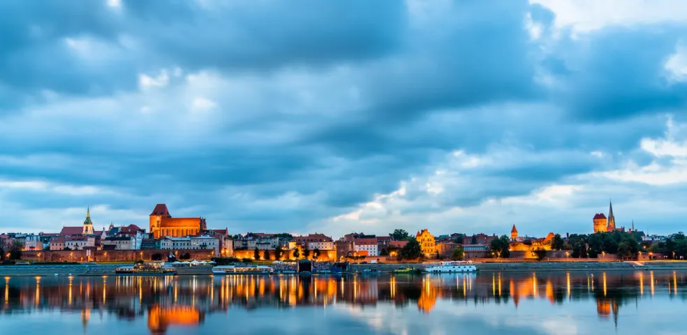 Toruń skyline at twilight reflected in the river.