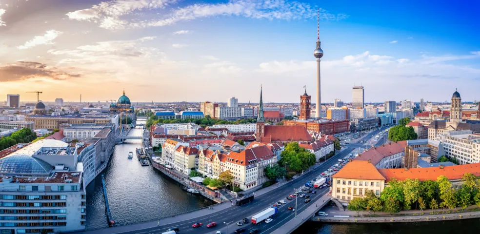 Panoramic view of Berlin's city center with the TV Tower, Berlin Cathedral, and the River Spree at sunset.