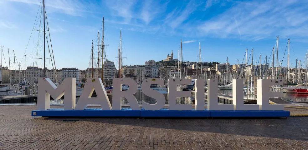 Marseille harbor with sailboats and city sign.
