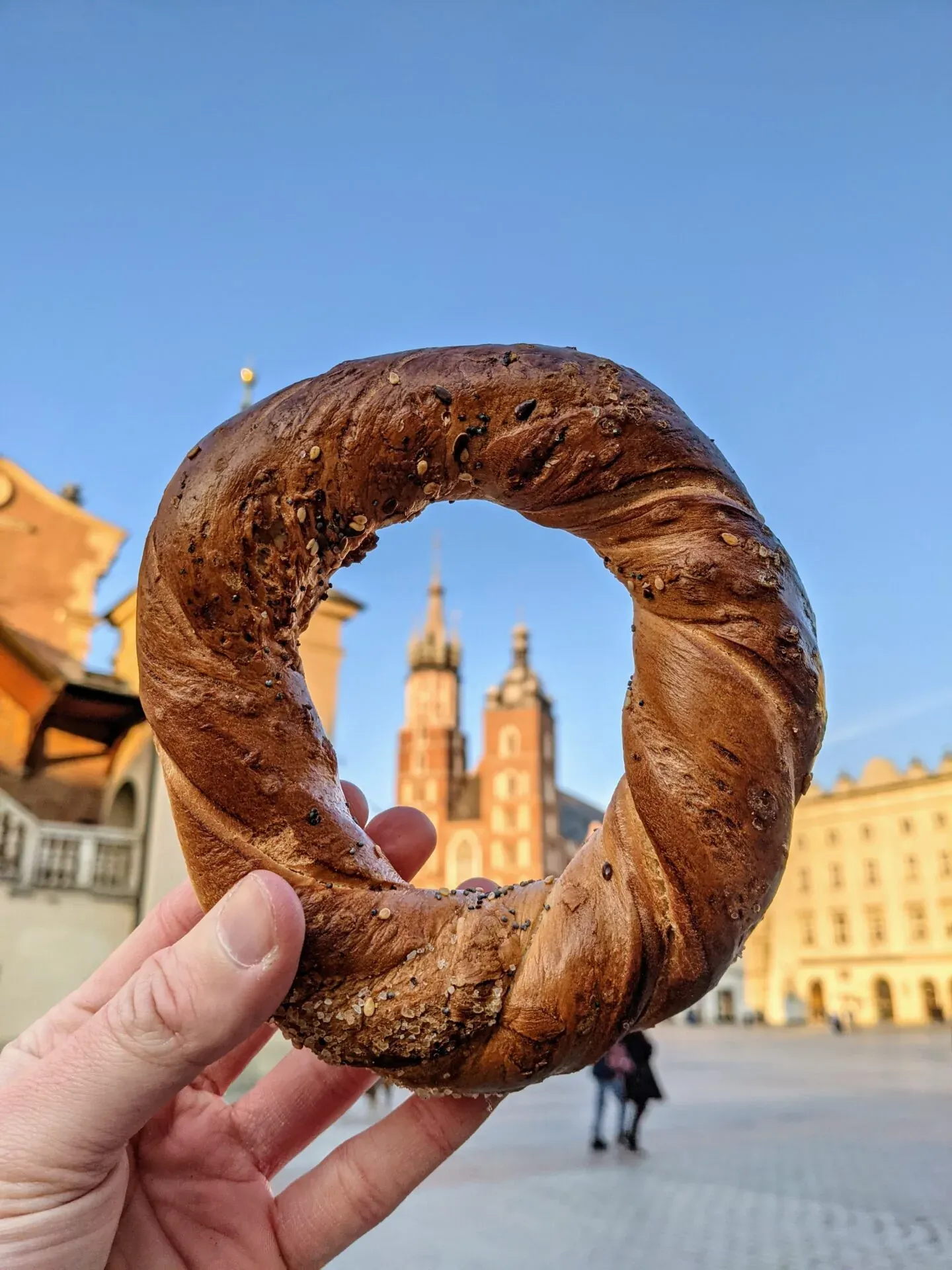 A delicious Krakow pretzel held up to frame St. Mary's Basilica.