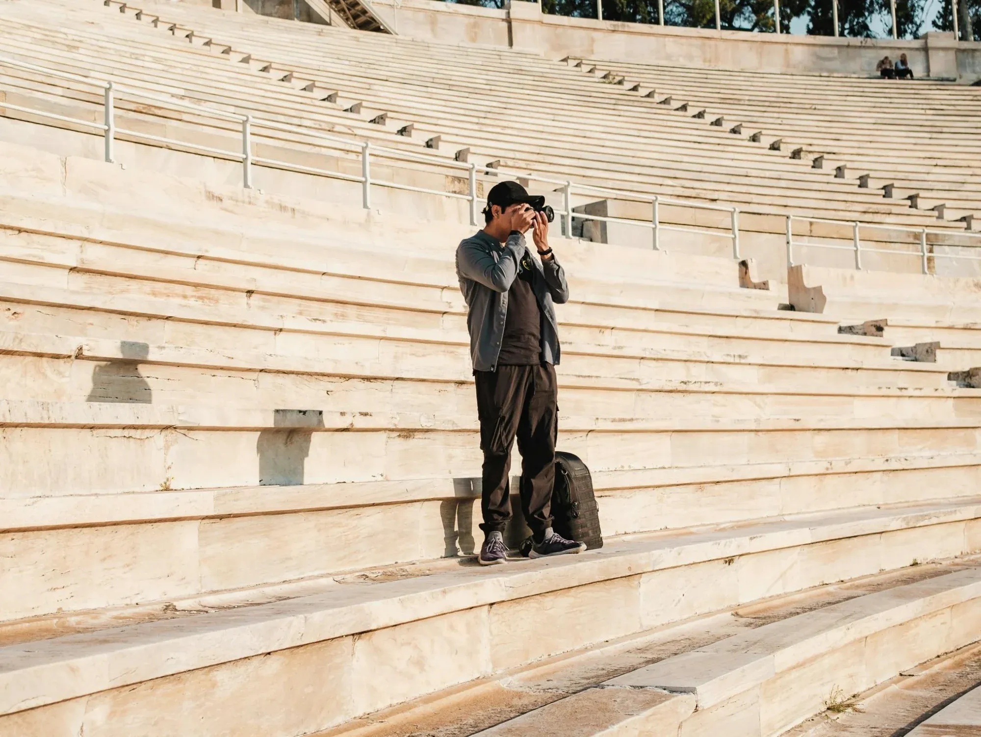 A photographer stands on the marble tiers of the Panathenaic Stadium in Athens taking a picture.