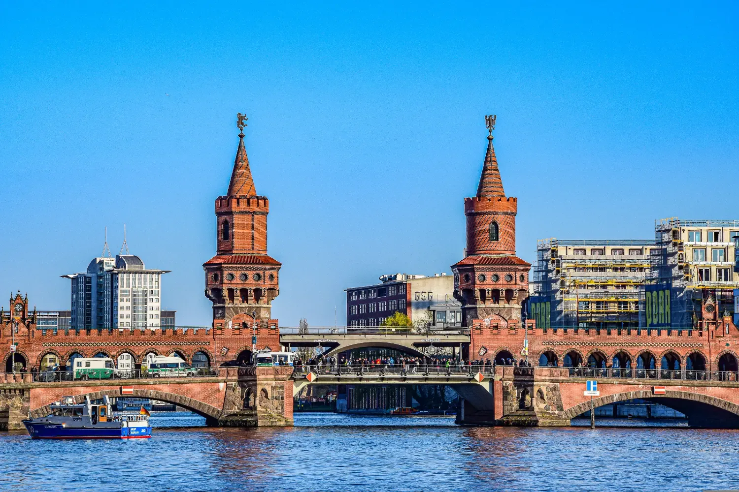 The Oberbaum Bridge with its two iconic red-brick towers spanning the Spree River on a sunny day in Berlin.