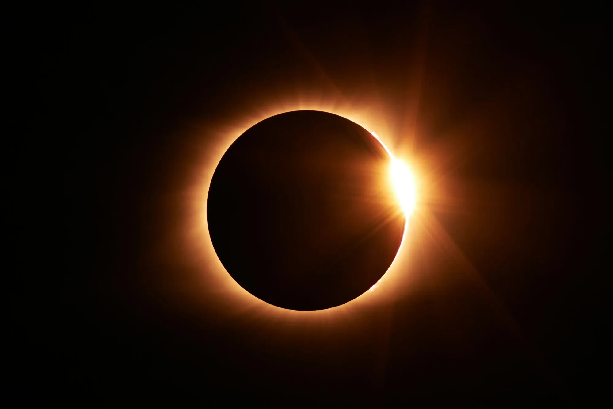 The moon obscures the sun during a total solar eclipse, with the sun's corona visible as a brilliant ring of light.