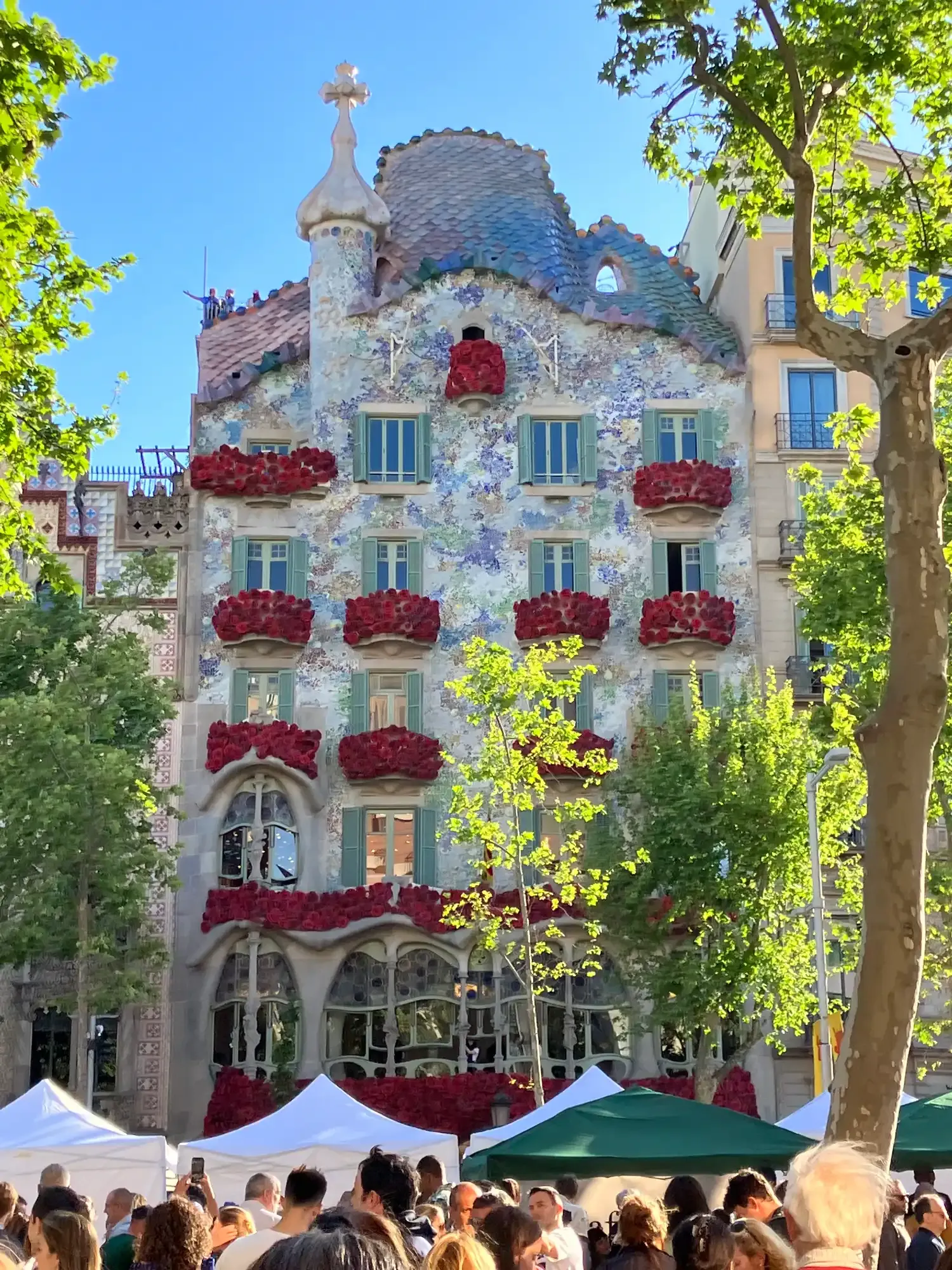 The facade of Gaudí's Casa Batlló in Barcelona, its balconies decorated with bright red roses for Sant Jordi day.