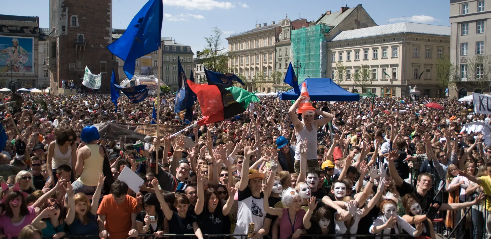 A huge crowd of students celebrating in Krakow's Main Market Square, with the Town Hall Tower in the background.