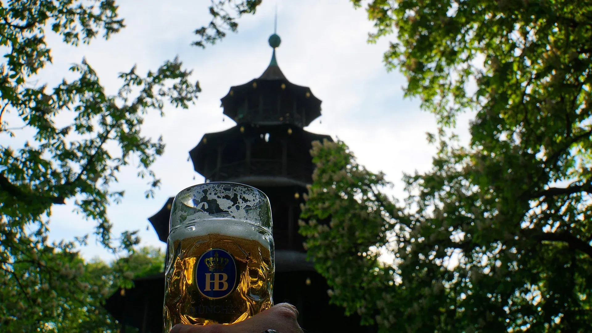 A beer mug held up in front of the Chinese Tower in the English Garden in Munich.