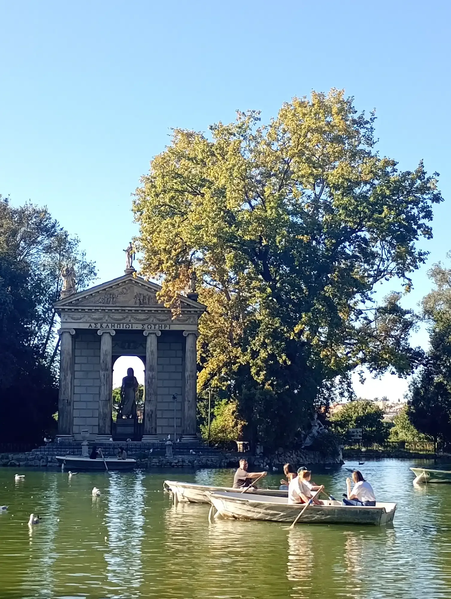 People rowing boats on the lake in Villa Borghese gardens near the Temple of Aesculapius in Rome.